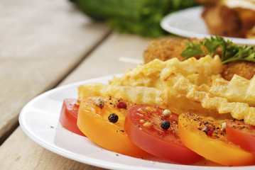 French fries and chicken on the plate on the wooden table