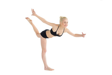 Obraz premium Full length of a sporty young woman balancing on one leg