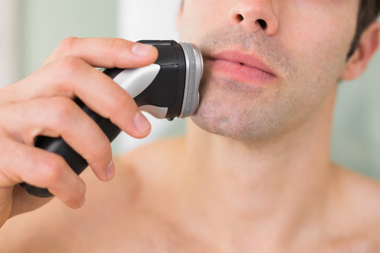 Extreme Close up of shirtless man shaving with electric razor