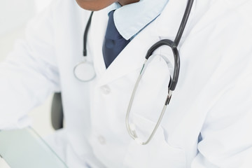 Mid section of doctor in lab coat and with stethoscope - Powered by Adobe