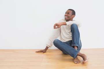 Afro man sitting on floor as he looks up to the wall