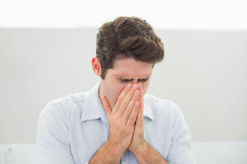 Sad casual young man with hands to his face