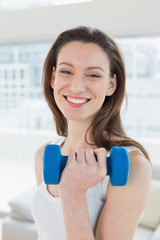 Fit woman exercising with dumbbell in fitness studio