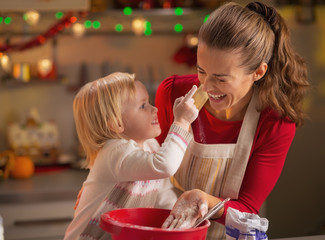 Baby trying to smear mothers nose with flour while making cookie