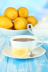 Cup of tea with lemon on table on blue background