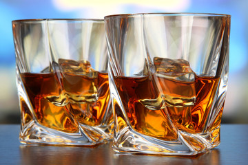 Glasses of whiskey, on bright background