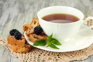 Cup of tea with cookies and blackberry on table close-up