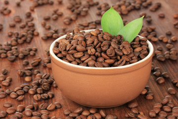 Coffee beans in bowl on wooden background