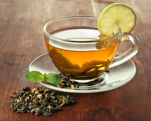 Transparent cup of green tea with lime on wooden background