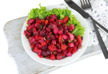 Beet salad on plate on napkin on wooden board isolated on white