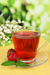 Delicious strawberry tea on table on bright background