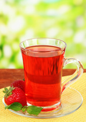 Delicious strawberry tea on table on bright background