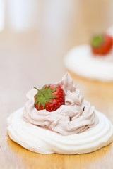 Meringue nest with cream and strawberry on wooden background