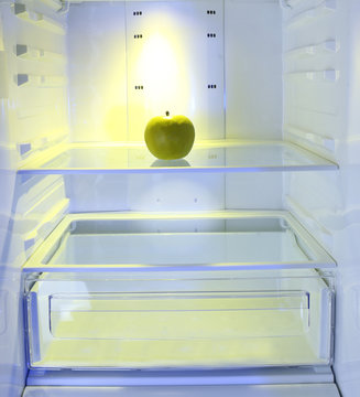 One apple in open empty refrigerator. Weight loss diet concept.