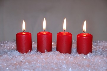 Vier rote Weihnachtskerzen im Schnee