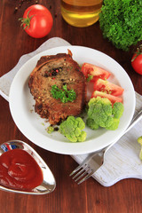 Piece of fried meat on plate on wooden table close-up