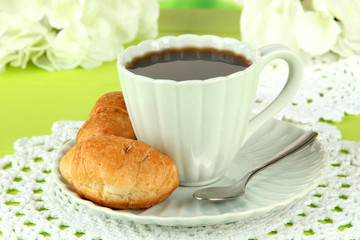 Tasty croissants and cup of coffee on table close-up