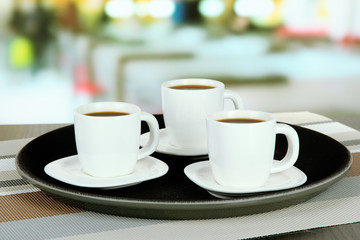Cups of coffee on tray on table in cafe