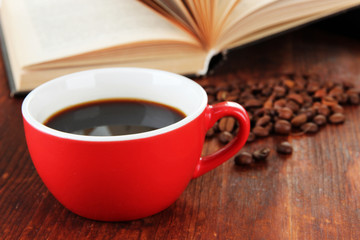 Cup of coffee with coffee beans and book on wooden background