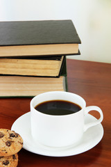 Cup of coffee with cookies and books