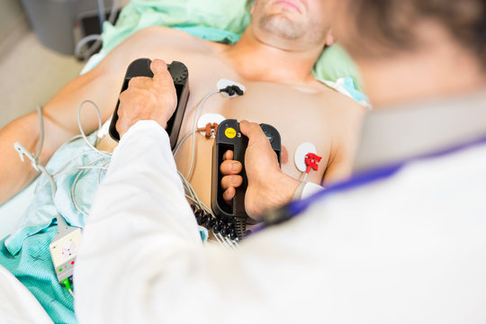 Doctor Defibrillating Male Patient In Hospital