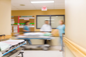 Doctor And Nurses With Stretcher In Hospital Corridor