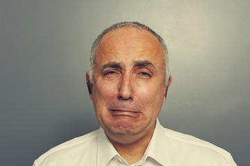 sorrowful senior man over grey background