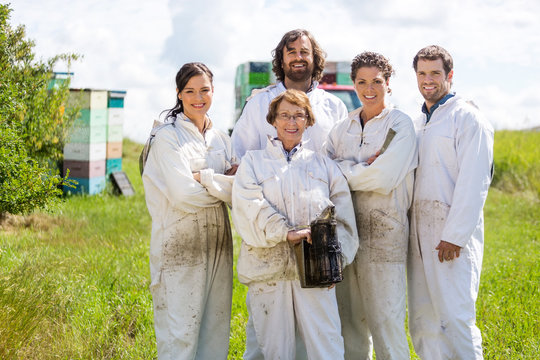 Team Of Confident Beekeepers At Apiary