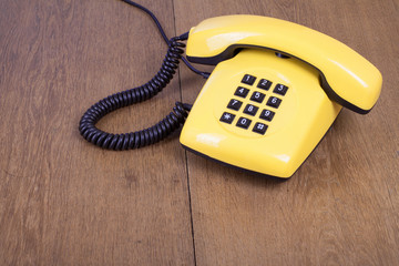 Retro yellow telephone on old wooden table background