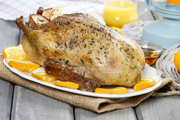 Roasted duck with oranges on wooden table