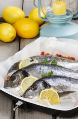 Gilt-head bream fishes in wicker basket on wooden table