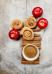 Bowl of cinnamon and cinnamon buns on wooden table