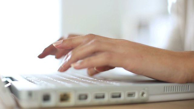 Woman's hand typing on laptop keyboard
