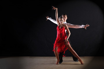 Latino dancers in ballroom against black background