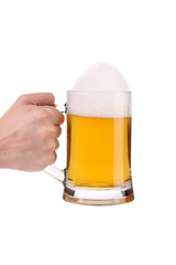 Hand holds mug of fresh beer with foam.
