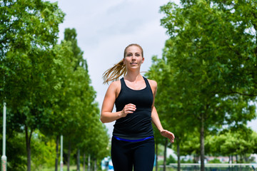 Sport und Fitness - Junge Frau joggt im Park