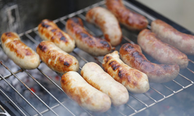 Baking bratwurst sausages on grill.