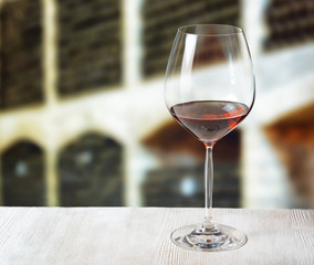 Glass of wine and wooden barrels in winery