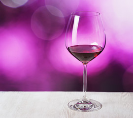Glass of red wine on purple background