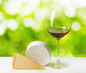 Cheese and glass of wine on nature background