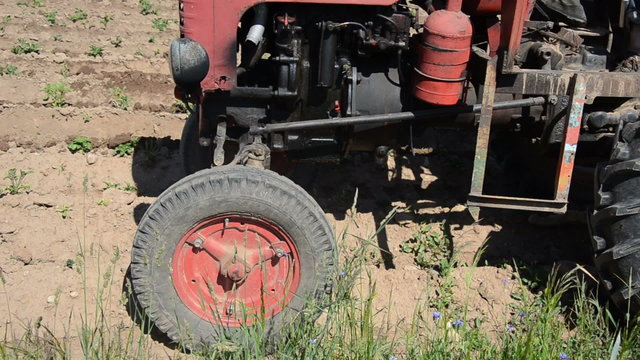 closeup of red retro handmade tractor work in agriculture field