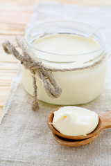 Obraz na płótnie Canvas homemade sour cream in a jar and on spoon