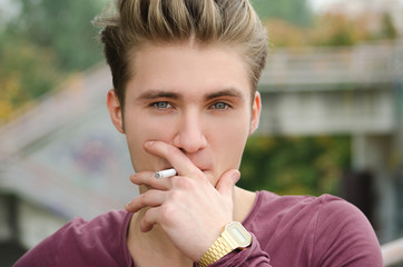 Handsome blond young man smoking cigarette
