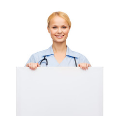 smiling female doctor or nurse with blank board