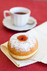 Fresh donut on a napkin with a cup of tea