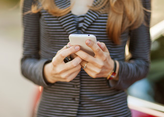 Fototapeta premium Young beautiful woman writes an SMS to your mobile phone.