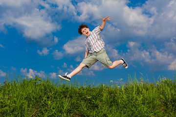 Boy jumping, running against blue sky