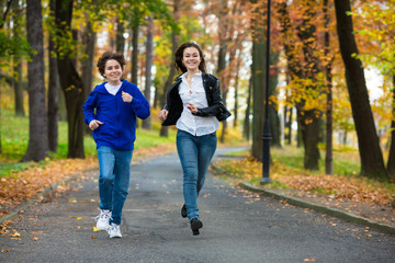 Girl and boy running, jumping in park