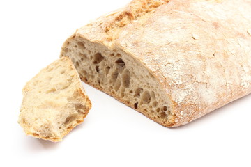 Bitten slice of rye bread and loaf in background