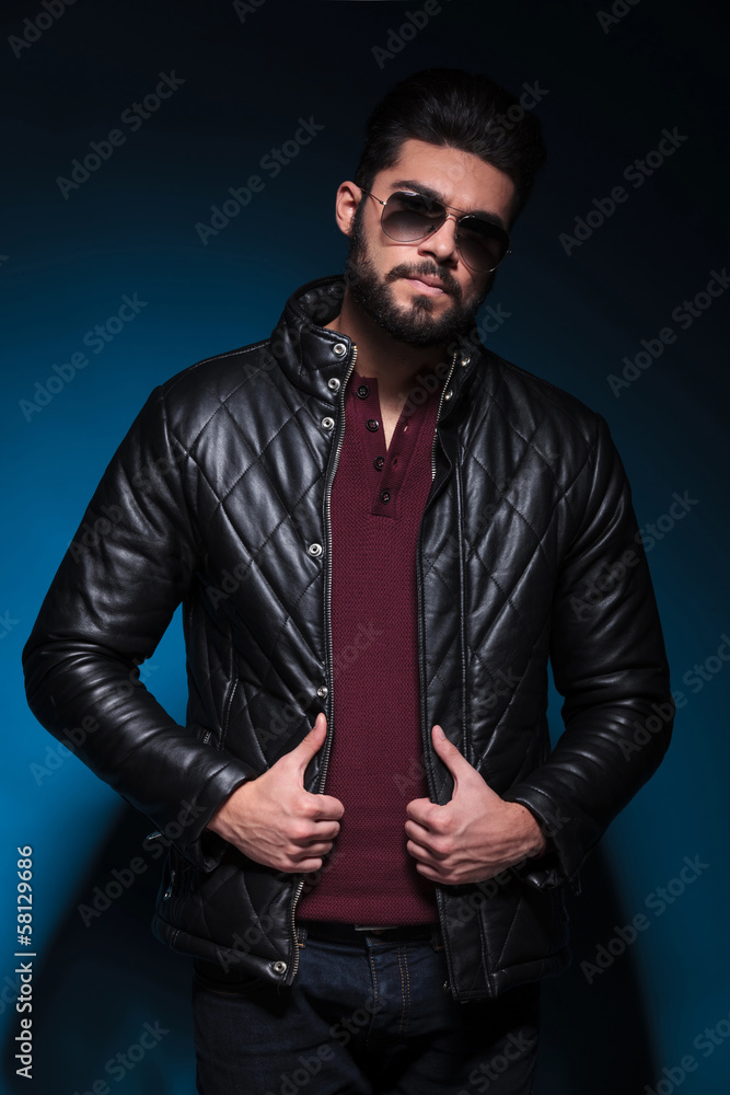 Poster young man with long beard is holding his leather jacket